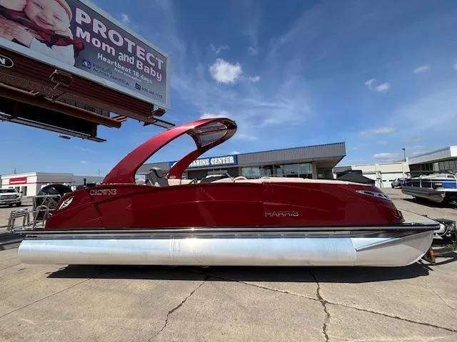 Slide: The Image of 2018 Harris Crowne SL 250 pontoon boat in a dealership lot under a clear blue sky. - 2