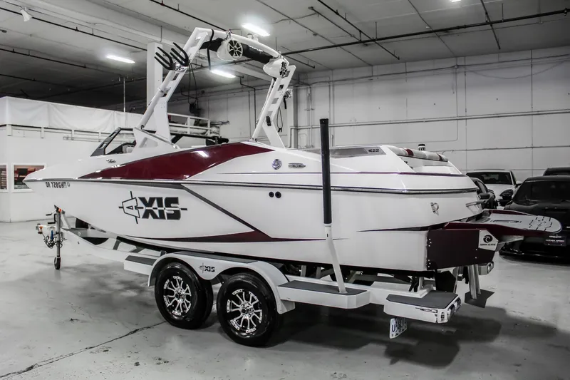Slide: The Image of 2018 Axis A22 boat in a garage, white and red design, on a trailer. - 2