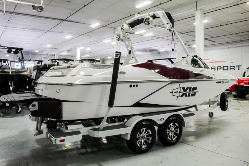 Slide: The Image of 2018 Axis A22 boat in showroom, white and maroon, on a dual-axle trailer. - 5