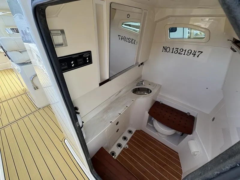 Slide: The Image of 2021 Grady-White Canyon 326 boat interior with wooden flooring and compact bathroom. - 15