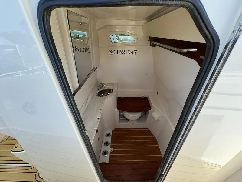 Slide: The Image of 2021 Grady-White Canyon 326 boat interior with compact bathroom and wooden flooring. - 16