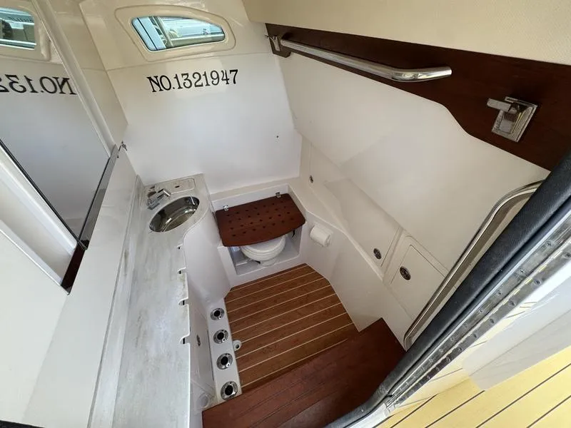 Slide: The Image of 2021 Grady-White Canyon 326 boat interior with compact bathroom and wooden flooring. - 17