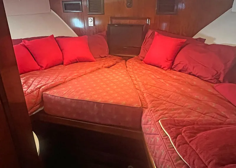 Slide: The Image of 1976 Hatteras Convertible cabin with red bedding and pillows, featuring wood paneling. - 23