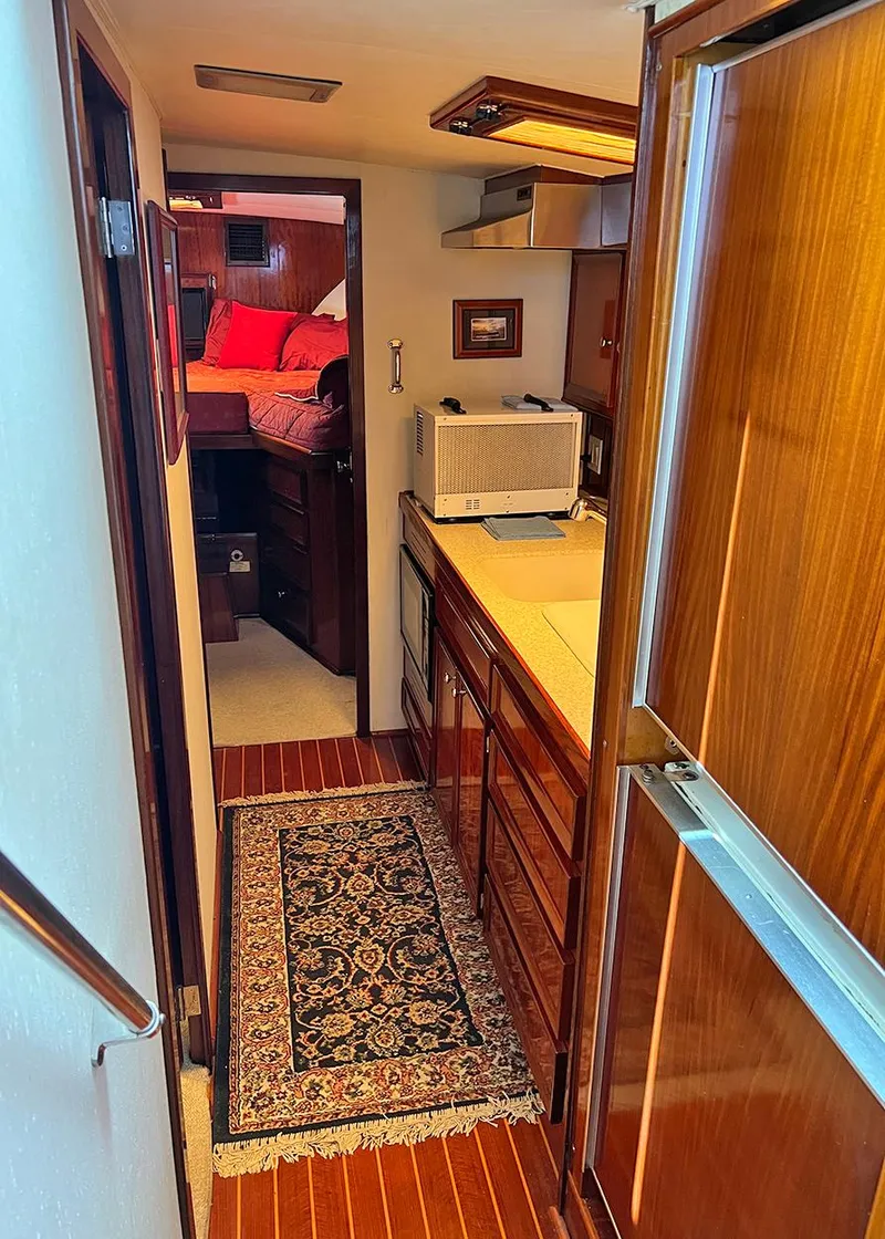 Slide: The Image of 1976 Hatteras Convertible yacht interior with wood paneling and compact kitchen area. - 24