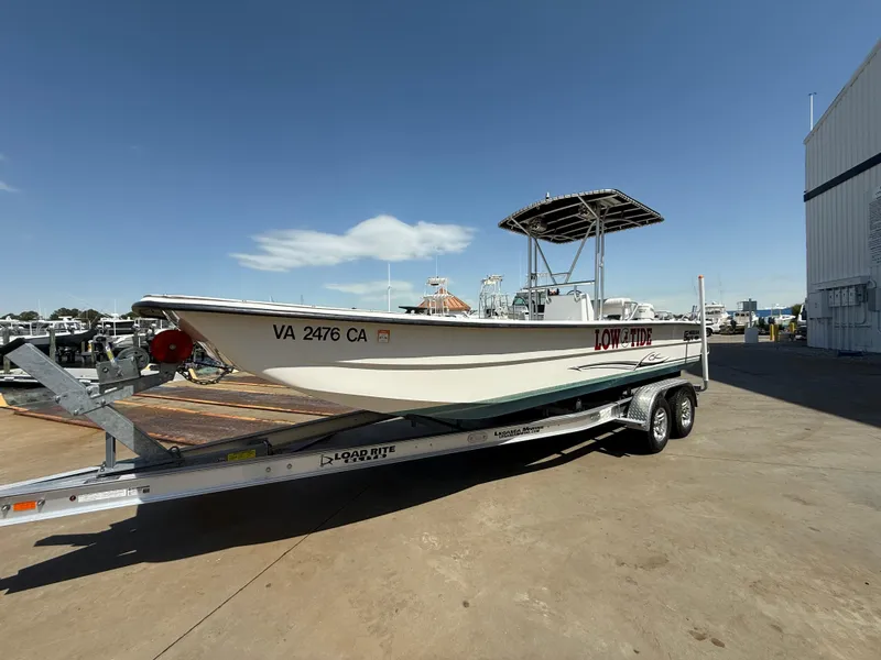 Slide: The Image of 2017 Carolina Skiff 24 DLX boat on trailer, parked outdoors under clear sky. - 0
