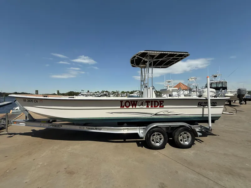 Slide: The Image of 2017 Carolina Skiff 24 DLX boat on trailer, dockside under clear blue sky. - 1