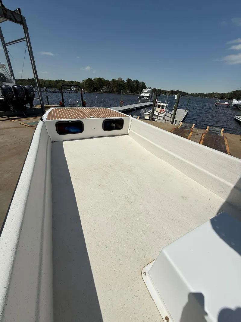 Slide: The Image of 2017 Carolina Skiff 24 DLX boat on dock, with water and trees in background. - 10