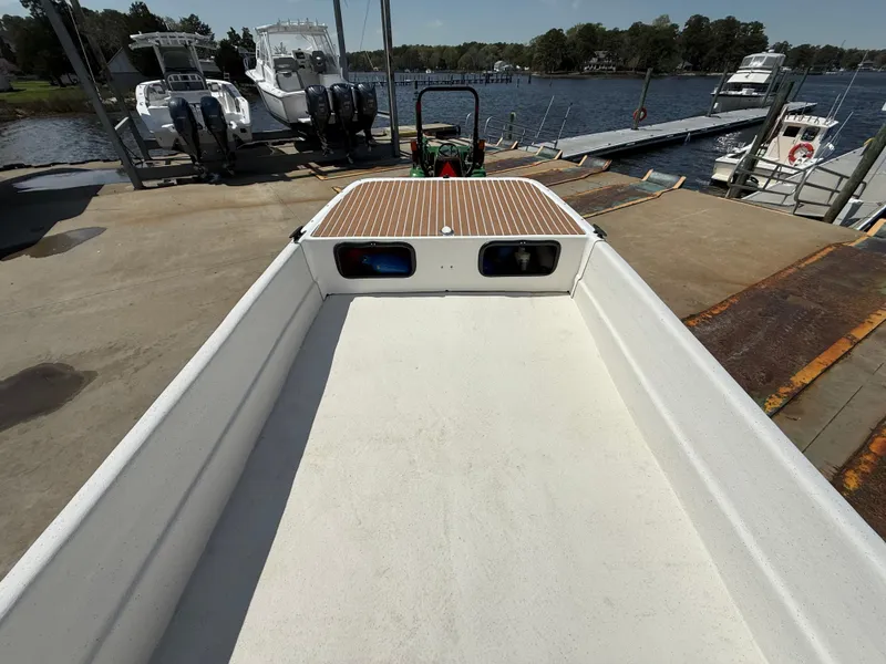 Slide: The Image of 2017 Carolina Skiff 24 DLX boat on a dock, with water and other boats in the background. - 11