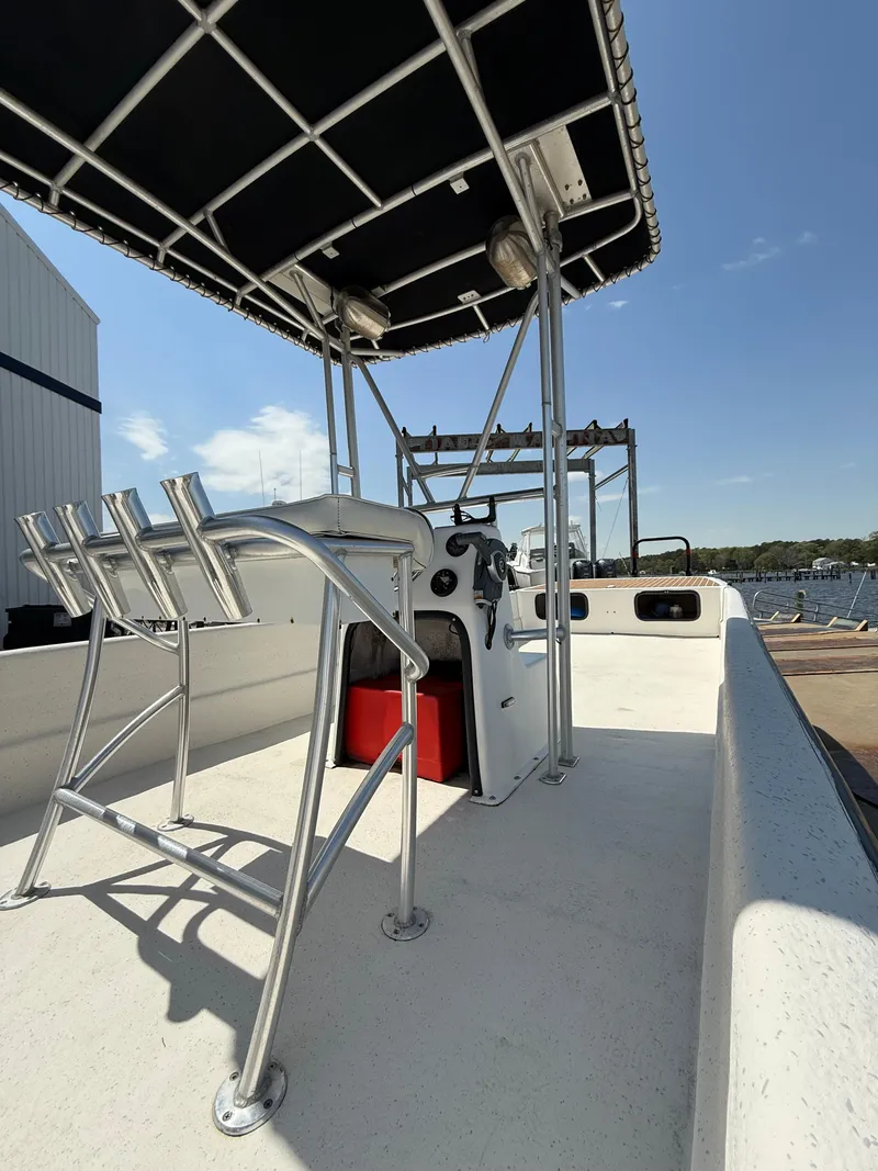 Slide: The Image of 2017 Carolina Skiff 24 DLX boat with T-top and console, docked by the water. - 6