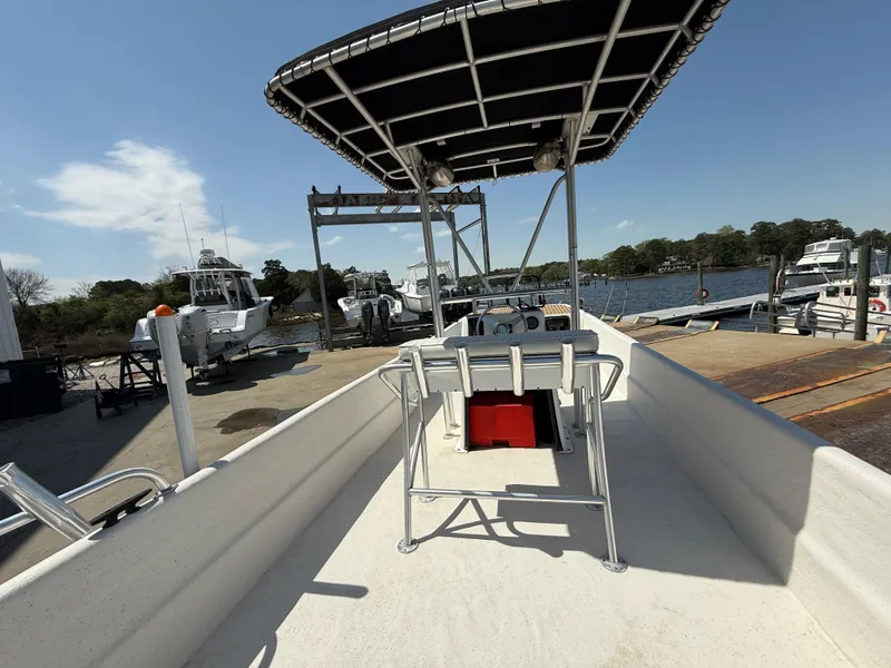 Slide: The Image of 2017 Carolina Skiff 24 DLX boat docked at a marina under a clear blue sky. - 7