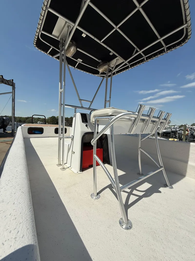 Slide: The Image of 2017 Carolina Skiff 24 DLX boat with T-top and seating, docked under clear sky. - 8