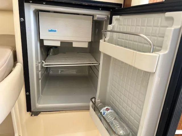 Slide: The Image of Open mini fridge inside 2006 Scout 262 Abaco boat, featuring a water bottle on the door shelf. - 26