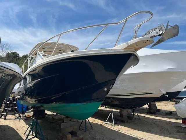 Slide: The Image of 2006 Scout 262 Abaco boat on stands, blue hull, clear sky background. - 4