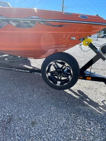 Slide: The Image of 2023 Crownline 220 SS LPX boat on trailer, vibrant orange hull, sunny day. - 11