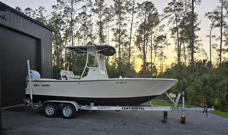 The Image of 2021 Sea Born LX22 Center Console boat on trailer, parked near forest at sunset. - 0