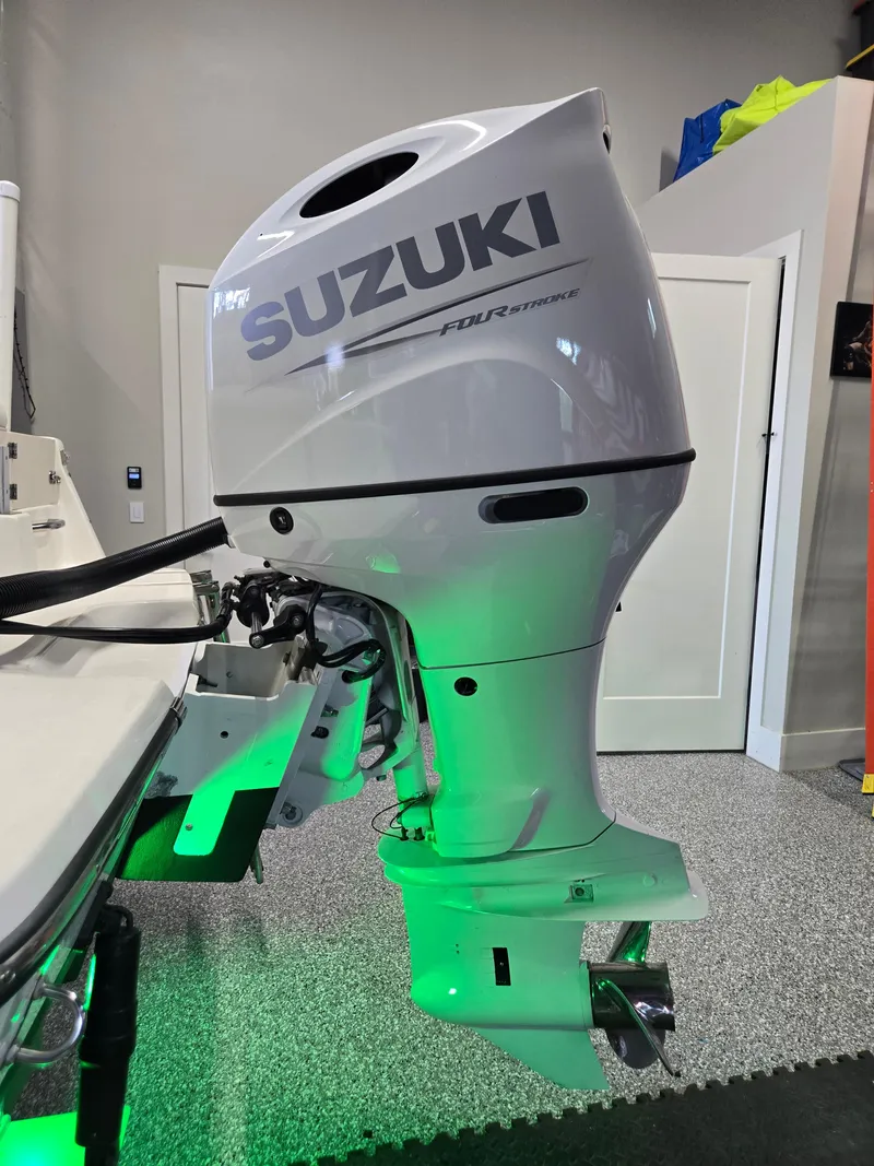 Slide: The Image of 2021 Sea Born LX22 Center Console with Suzuki outboard motor in a garage setting. - 2