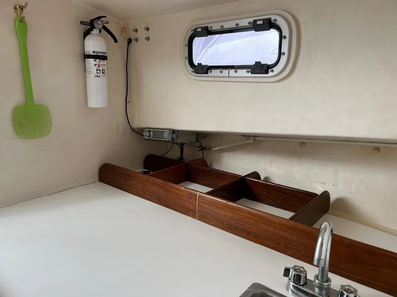 Slide: The Image of Interior of 1986 Dyer 29 Trunk Cabin with window, fire extinguisher, and sink. - 18