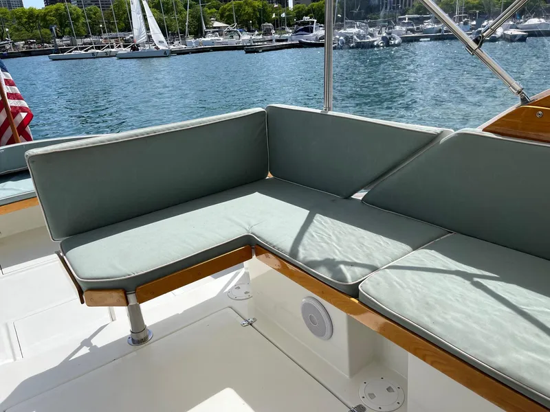 Slide: The Image of Cozy seating area on a 1986 Dyer 29 Trunk Cabin boat, docked at a marina. - 25