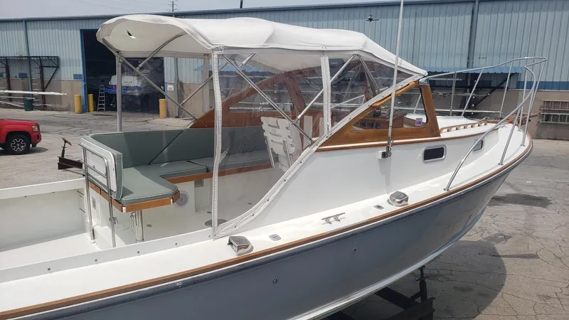 Slide: The Image of 1986 Dyer 29 Trunk Cabin boat with canopy, docked in an industrial area. - 31