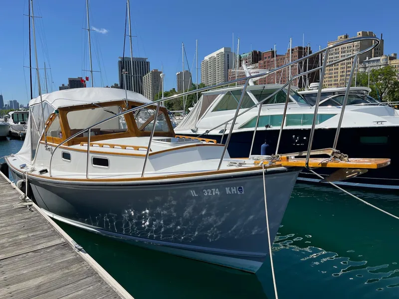 Slide: The Image of 1986 Dyer 29 Trunk Cabin boat docked in a marina with city skyline background. - 6