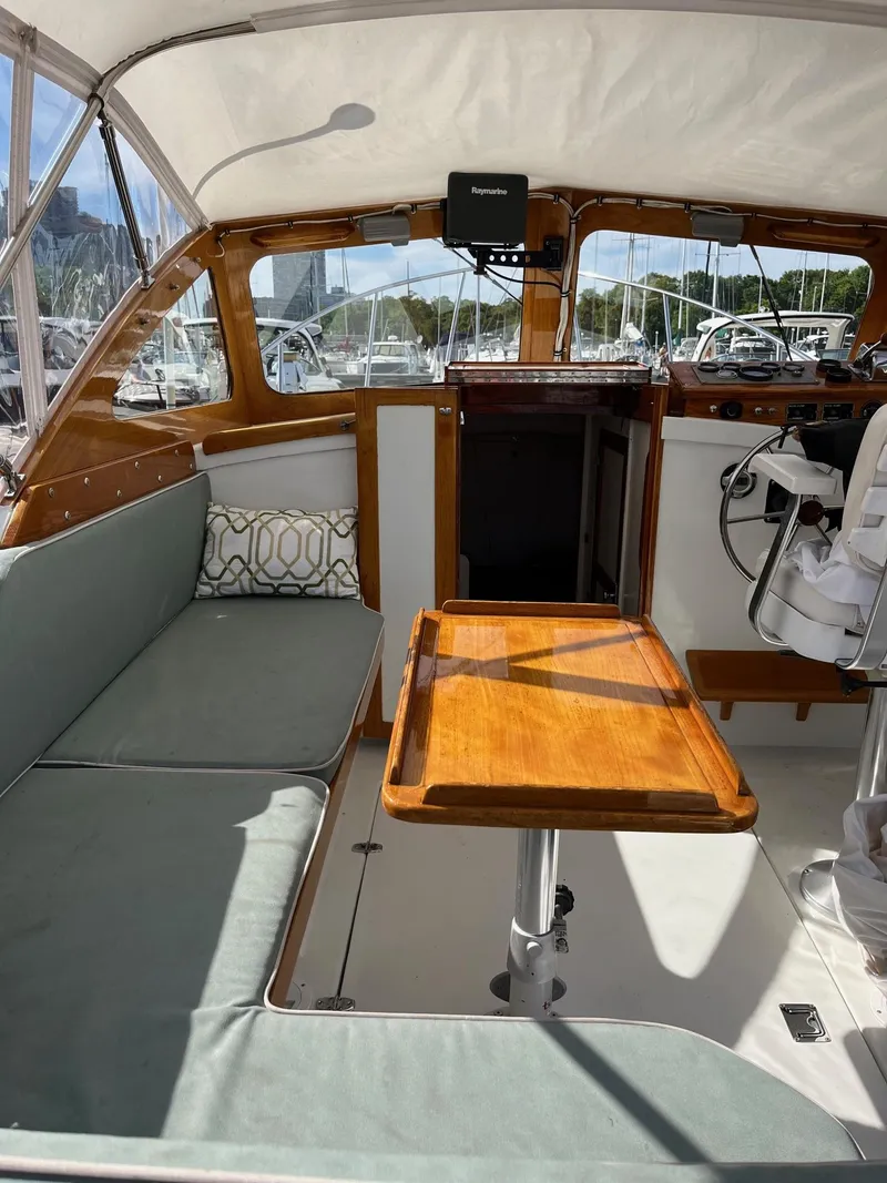 Slide: The Image of 1986 Dyer 29 Trunk Cabin interior with cushioned seating and wooden table. - 8