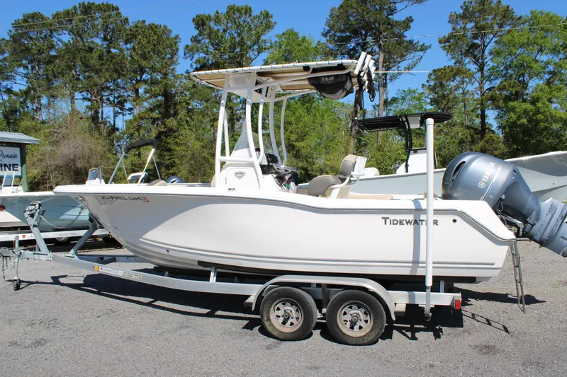 Slide: The Image of 2019 Tidewater 210 CC Adventure boat on trailer, parked outdoors with trees in background. - 5