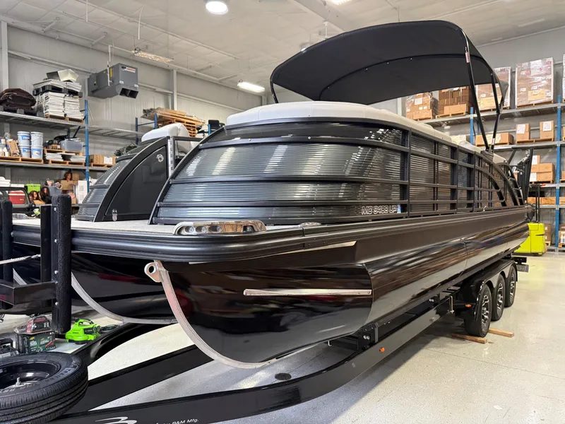 Slide: The Image of 2022 Bennington 25 QSBSG pontoon boat in showroom, black exterior, on trailer. - 1