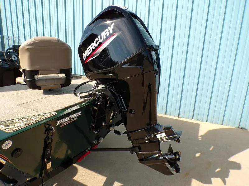 Slide: The Image of 2025 Tracker Bass Tracker® Classic Limited with Mercury outboard motor, parked near blue wall. - 6