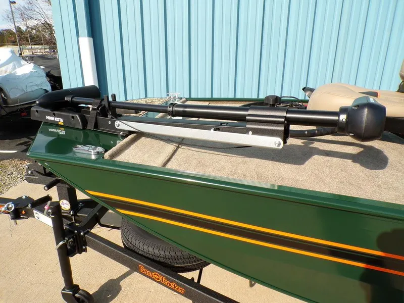 Slide: The Image of 2025 Tracker Bass Tracker® Classic Limited boat with trolling motor, green exterior, parked by blue building. - 9