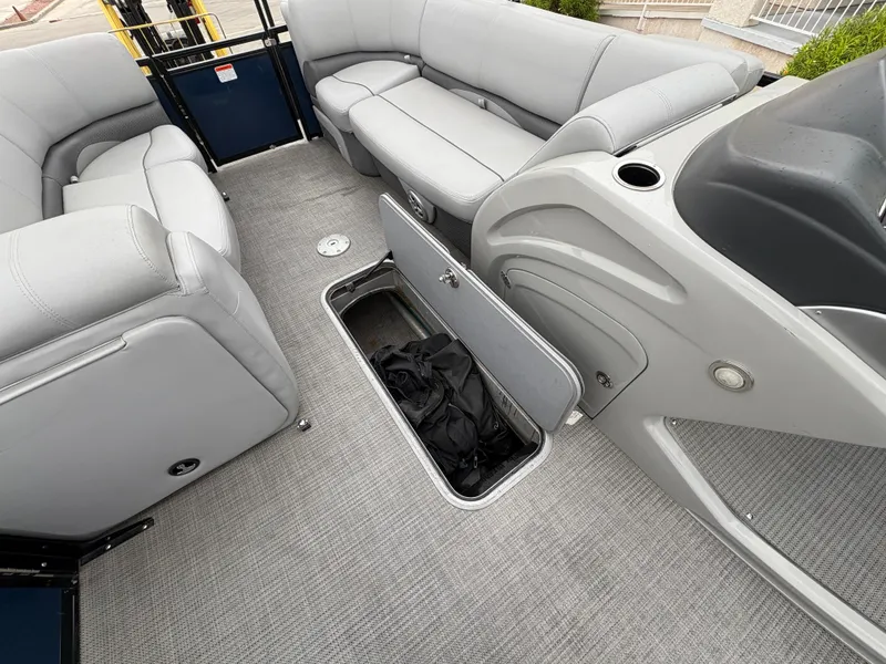 Slide: The Image of 2019 Regency 210 DL3 boat interior with open storage compartment and gray seating. - 11