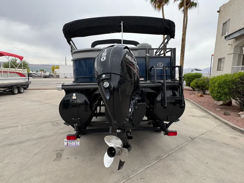 Slide: The Image of 2019 Regency 210 DL3 pontoon boat with Mercury outboard motor, parked on a trailer. - 3