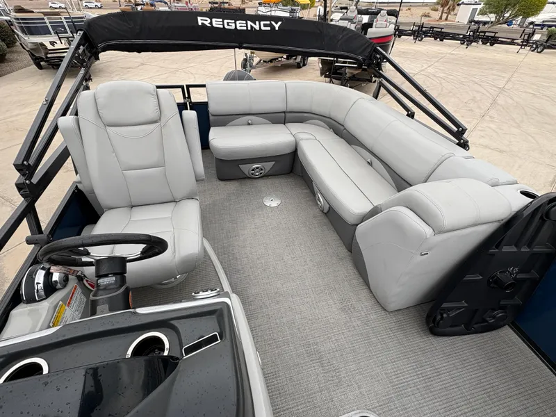 Slide: The Image of 2019 Regency 210 DL3 pontoon boat interior with gray seating and steering console. - 6