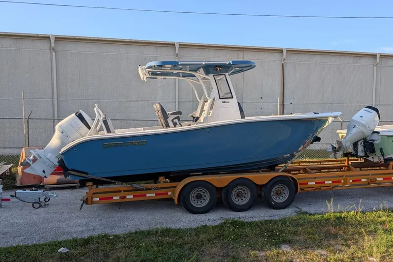 Slide: The Image of 2025 Sea Pro 245 FLX boat on trailer, blue hull, dual engines, parked outdoors. - 1