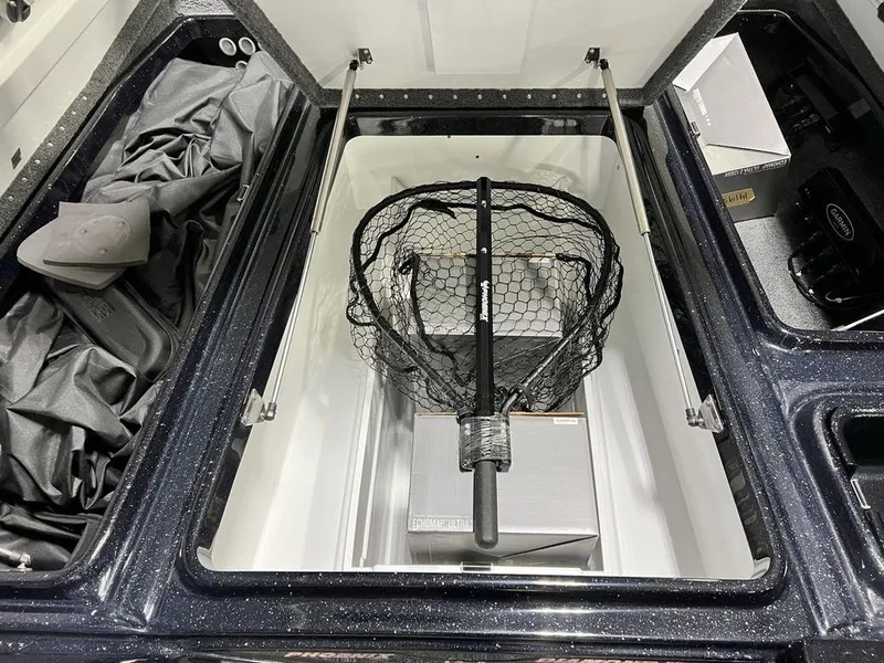 Slide: The Image of Open storage compartment in 2025 Phoenix 920 Elite boat with fishing net and accessories. - 14