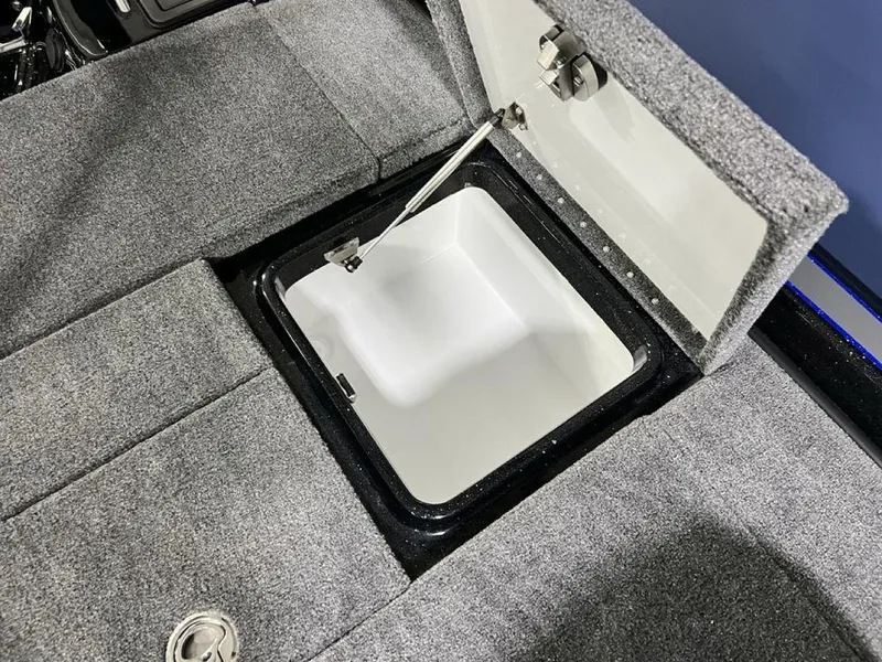 Slide: The Image of Open storage compartment in 2025 Phoenix 920 Elite boat, featuring gray carpeted interior. - 27
