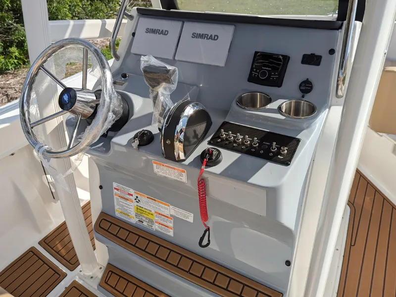Slide: The Image of 2025 Bayliner Trophy T20CC boat console with steering wheel, controls, and Simrad displays. - 13