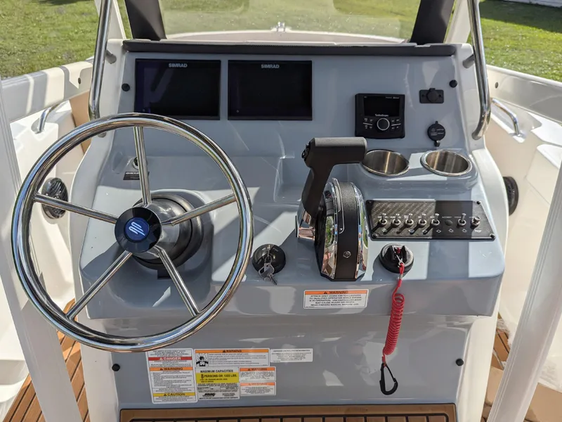 Slide: The Image of 2025 Bayliner Trophy T20CC boat dashboard with steering wheel, controls, and dual displays. - 14