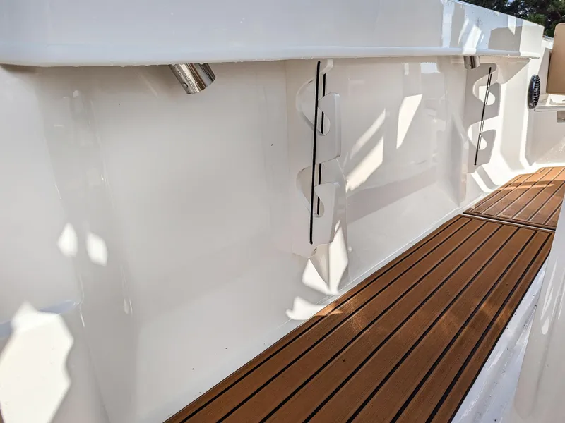 Slide: The Image of 2025 Bayliner Trophy T20CC boat deck with sleek wood finish and rod holders. - 16