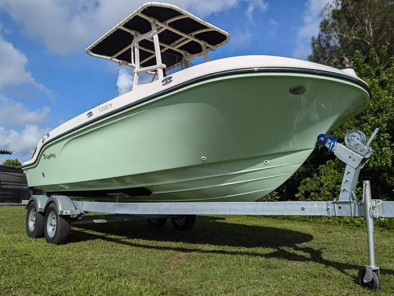 Slide: The Image of 2025 Bayliner Trophy T20CC boat on trailer, parked on grass under blue sky. - 2