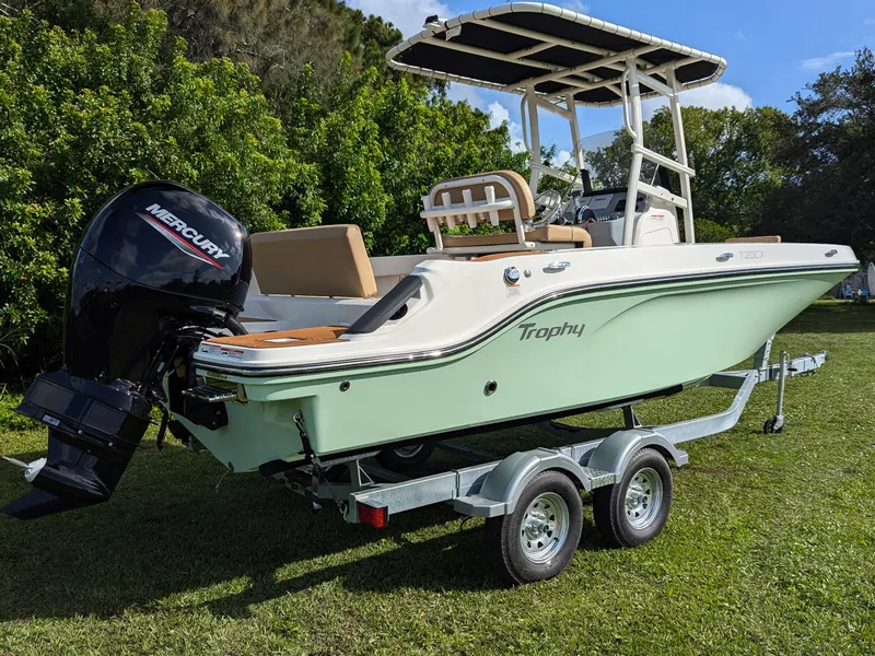 Slide: The Image of 2025 Bayliner Trophy T20CC boat on trailer, featuring Mercury outboard motor, parked on grass. - 3
