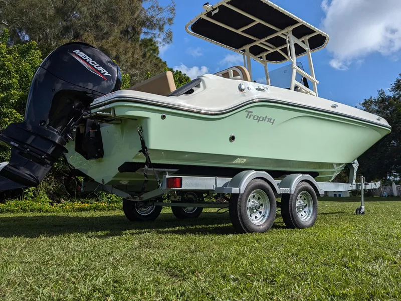 Slide: The Image of 2025 Bayliner Trophy T20CC boat on trailer, green hull, Mercury outboard, parked on grass. - 4