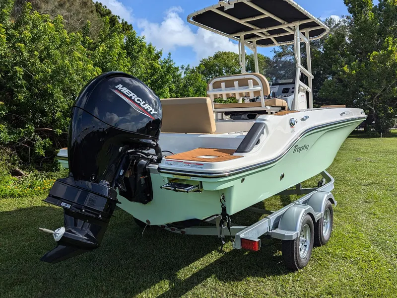 Slide: The Image of 2025 Bayliner Trophy T20CC boat on trailer with Mercury outboard motor, parked on grass. - 5