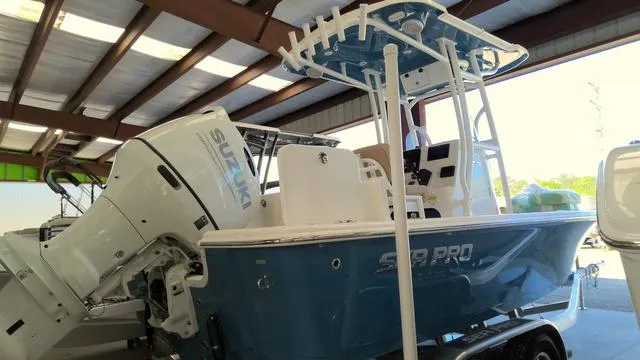 Slide: The Image of 2025 Sea Pro 210 Bay boat with Suzuki outboard motor in a covered storage area. - 21