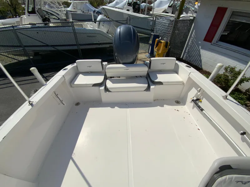 Slide: The Image of 2015 Tidewater 196 DC Explorer boat interior with seating and motor, docked outdoors. - 15