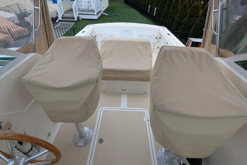 Slide: The Image of 2004 Hunt Yachts Surfhunter 25 cockpit with covered seats and helm, showcasing spacious design. - 19