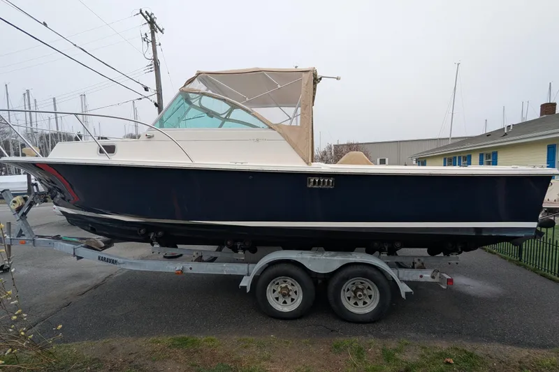 Slide: The Image of 2004 Hunt Yachts Surfhunter 25 on trailer, navy hull, beige canopy, parked outdoors. - 2