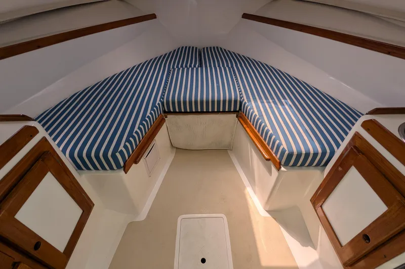 Slide: The Image of 2004 Hunt Yachts Surfhunter 25 cabin interior with striped cushions and wooden accents. - 24