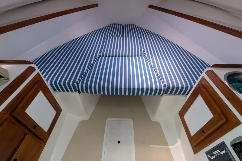 Slide: The Image of 2004 Hunt Yachts Surfhunter 25 cabin interior with striped cushions and wooden cabinetry. - 25