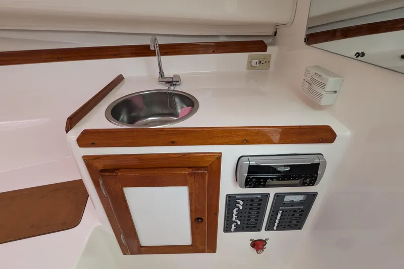 Slide: The Image of 2004 Hunt Yachts Surfhunter 25 interior with sink, control panel, and wooden cabinetry. - 27
