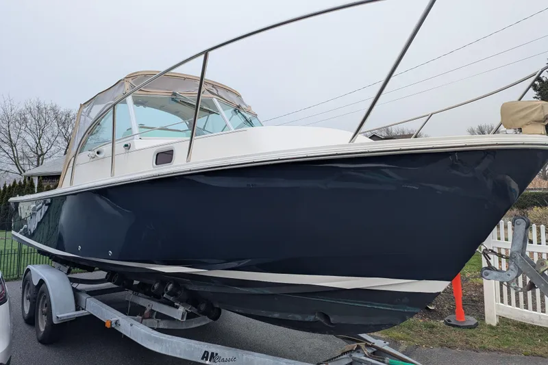 Slide: The Image of 2004 Hunt Yachts Surfhunter 25 on trailer, navy hull, parked outdoors. - 4